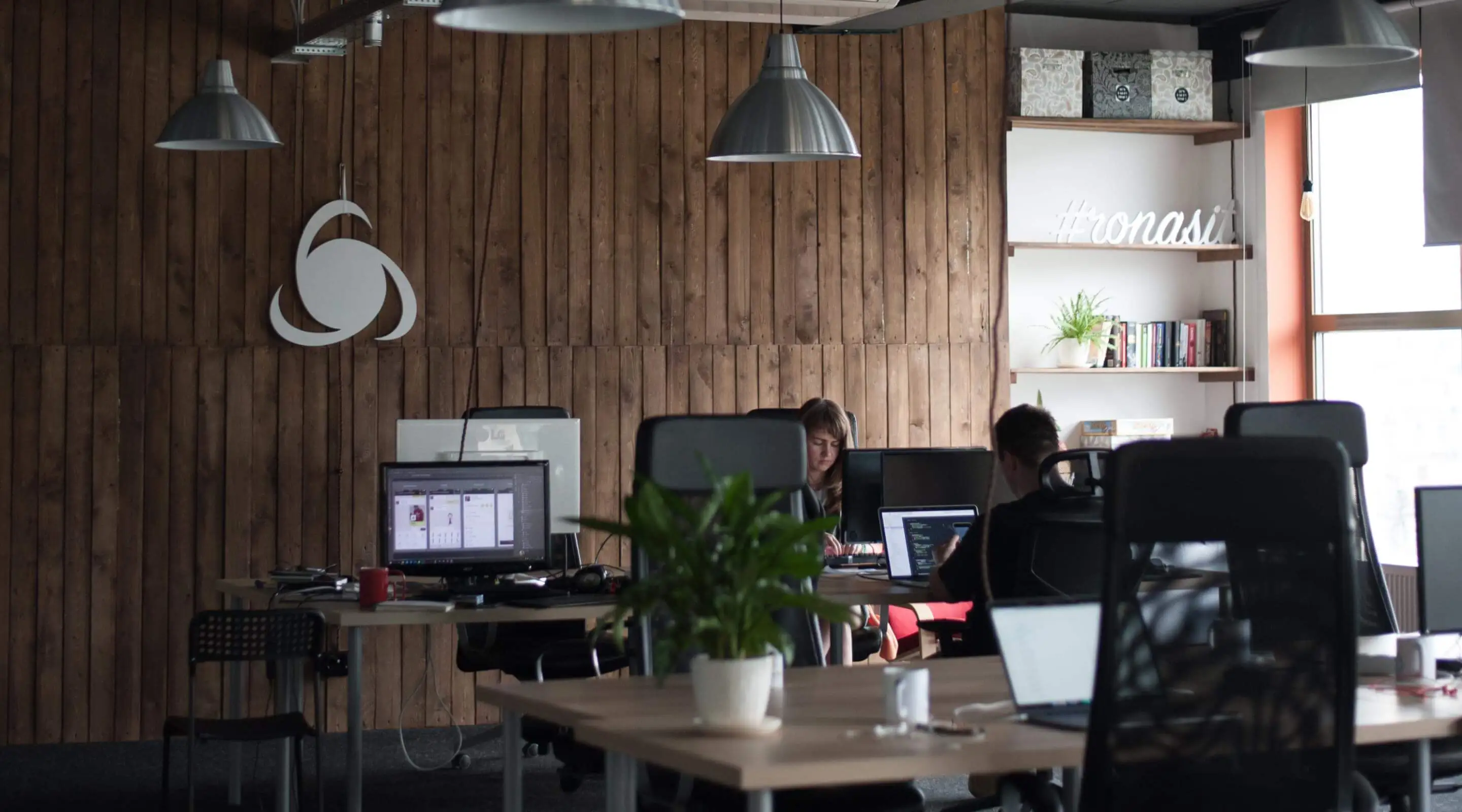 Ronas IT open space office with the company logo on the wooden wall
