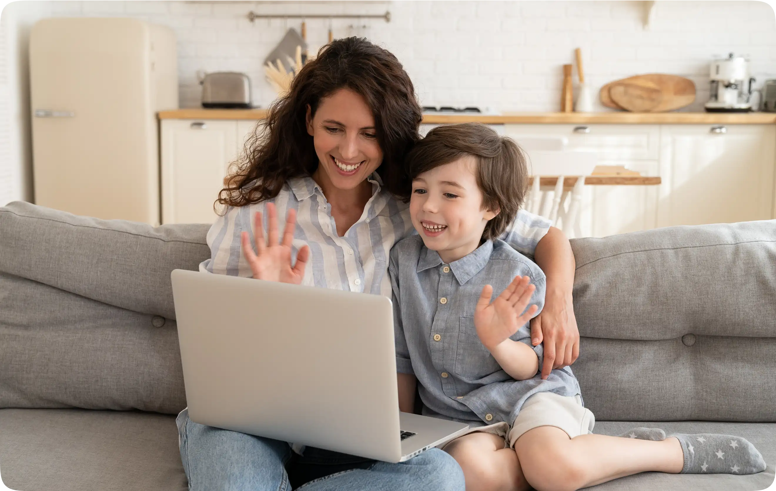 Woman and child on a couch waving during a video learning call on a laptop.