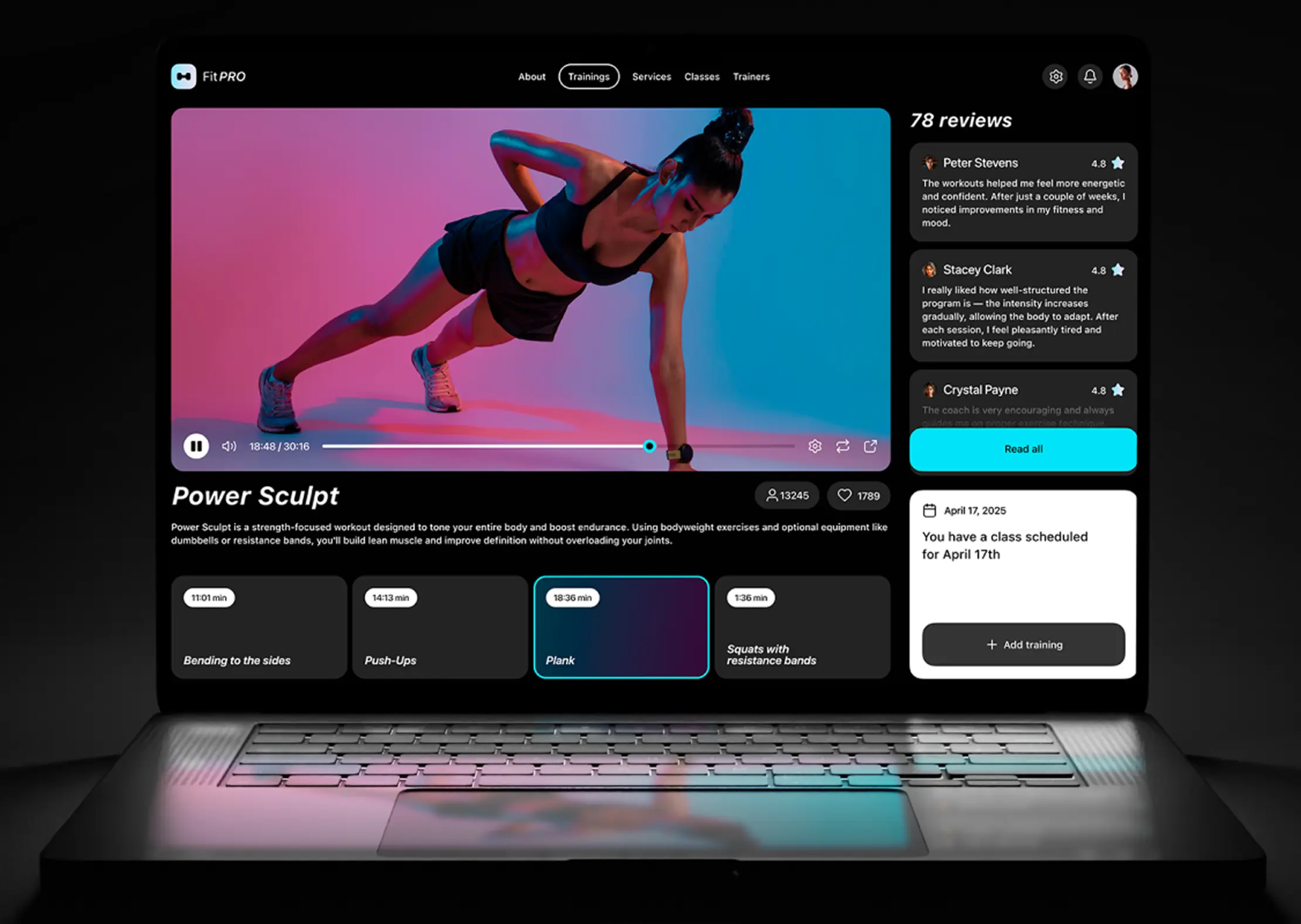 Laptop with a dark fitness app workout page featuring a video player and user reviews.