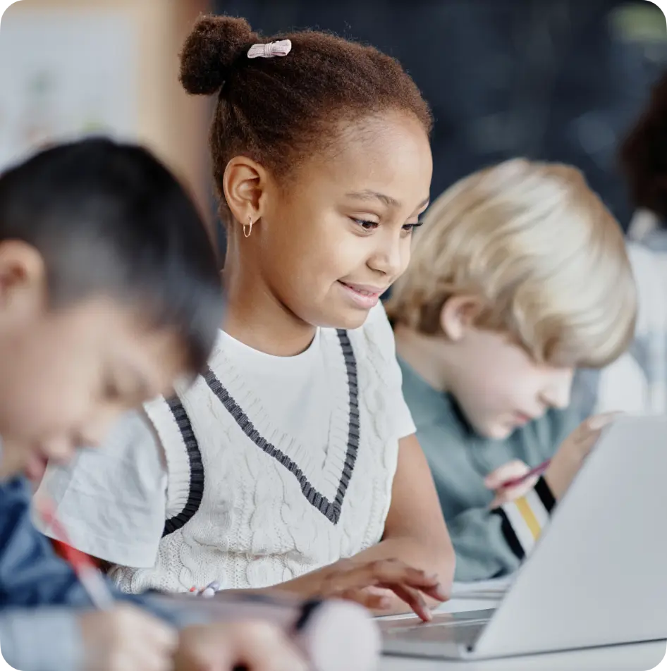 Young student smiling at a desk in a classroom using the virtual classroom.