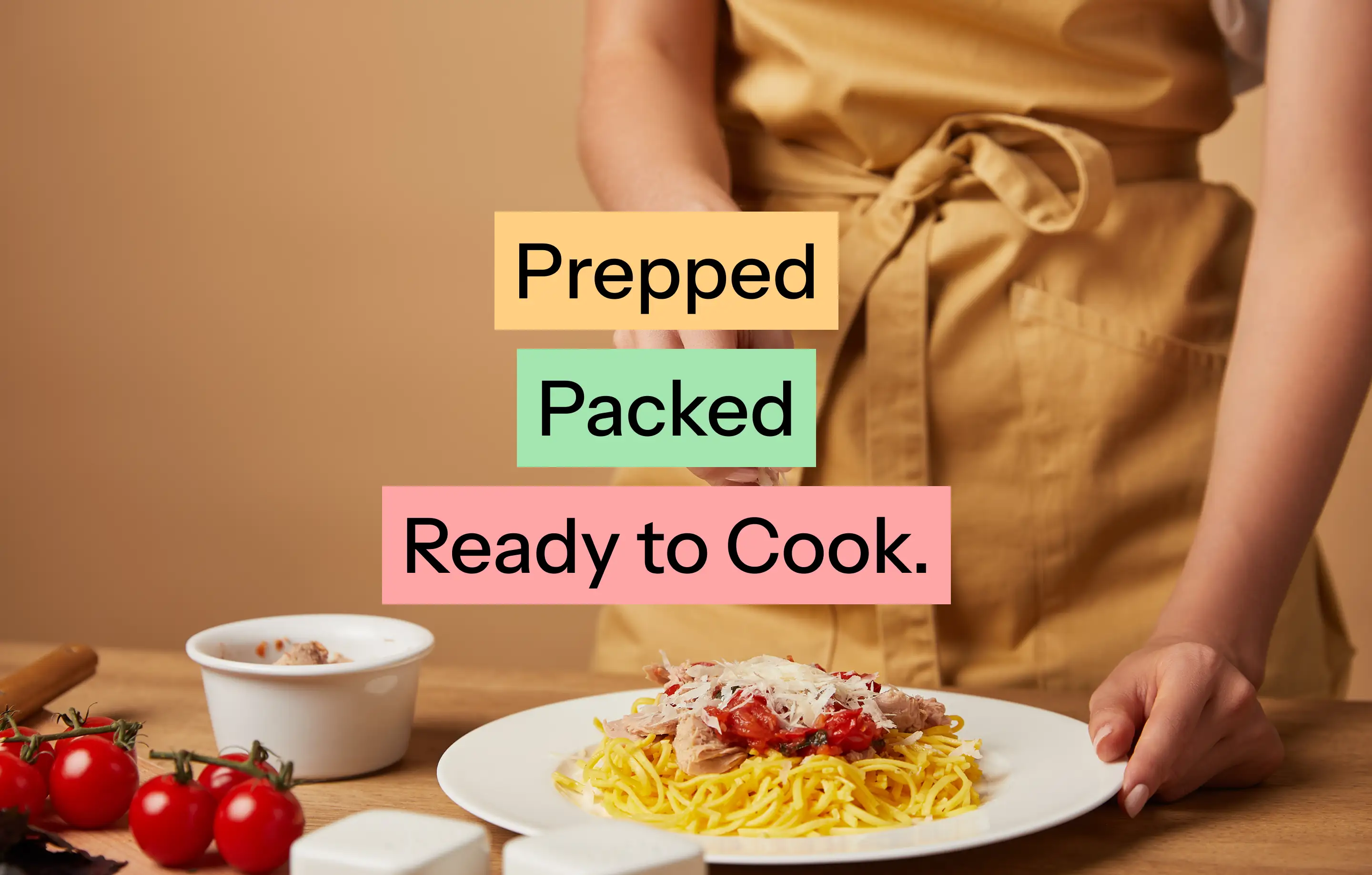 Cook in an apron plating pasta, overlaid with the words Prepped, Packed, Ready to Cook.