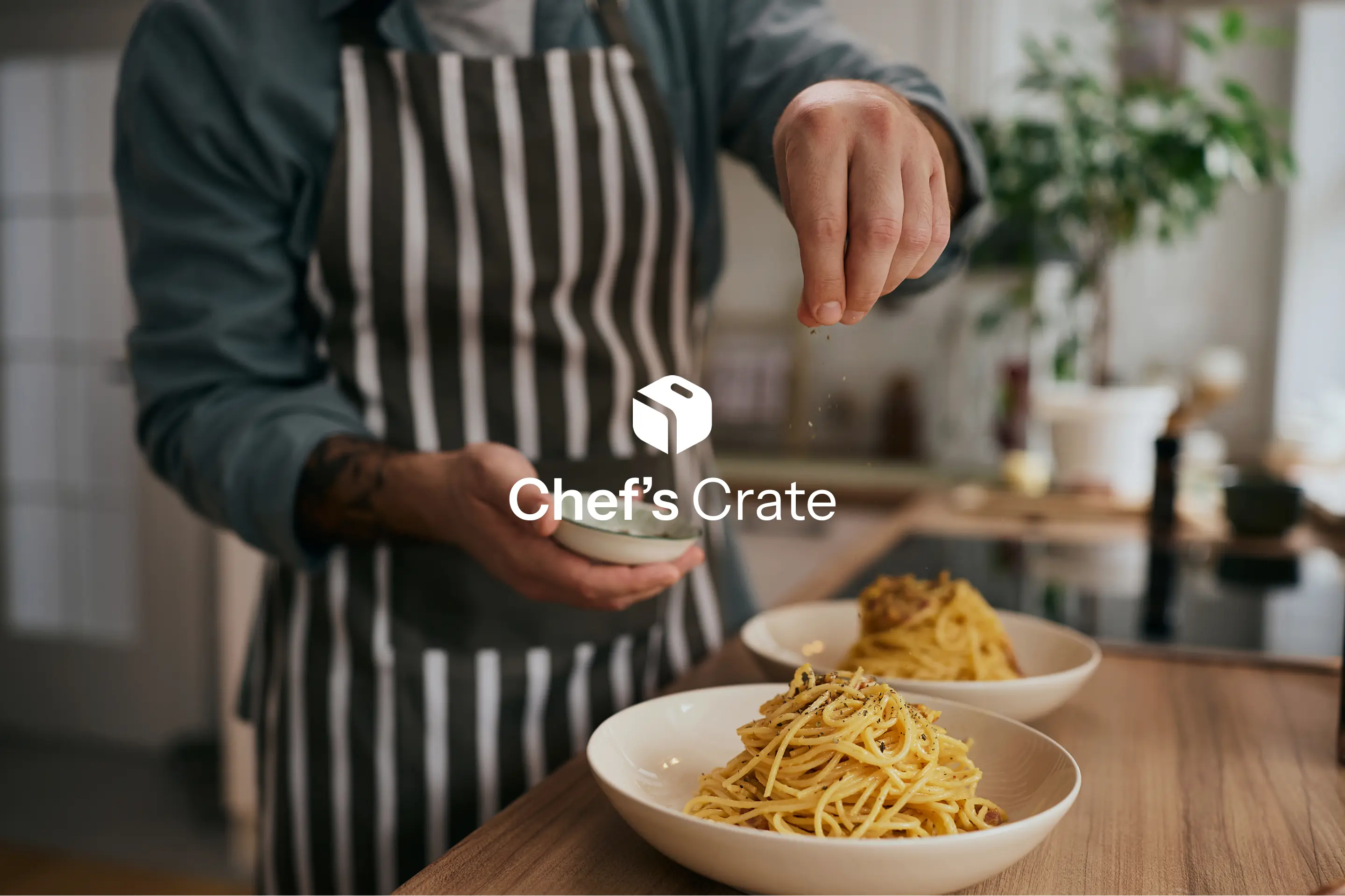 Cook in a striped apron seasoning bowls of pasta, with the Chef's Crate logo over the photo.
