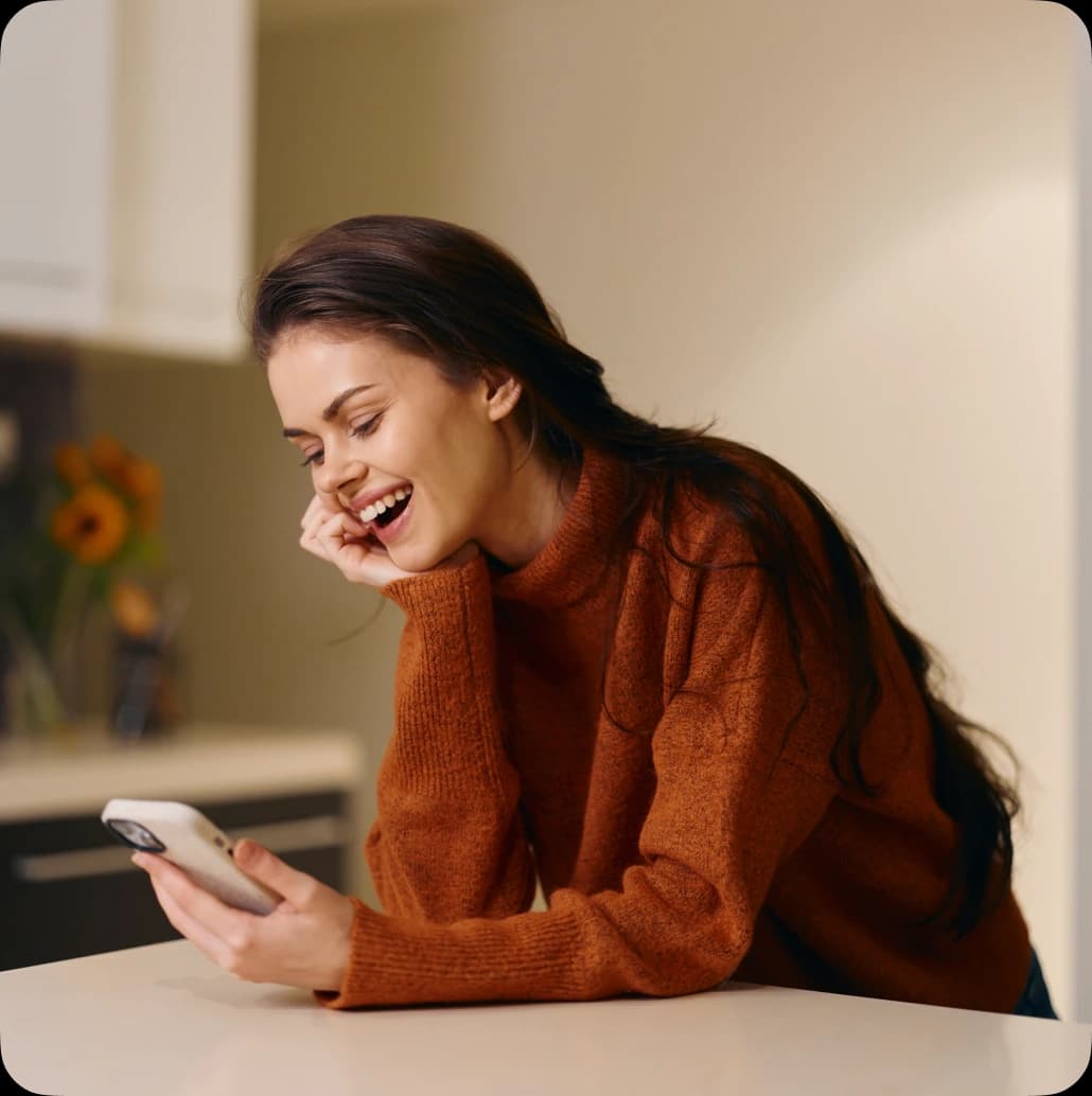 Smiling woman holding a smartphone running the smart-home app.