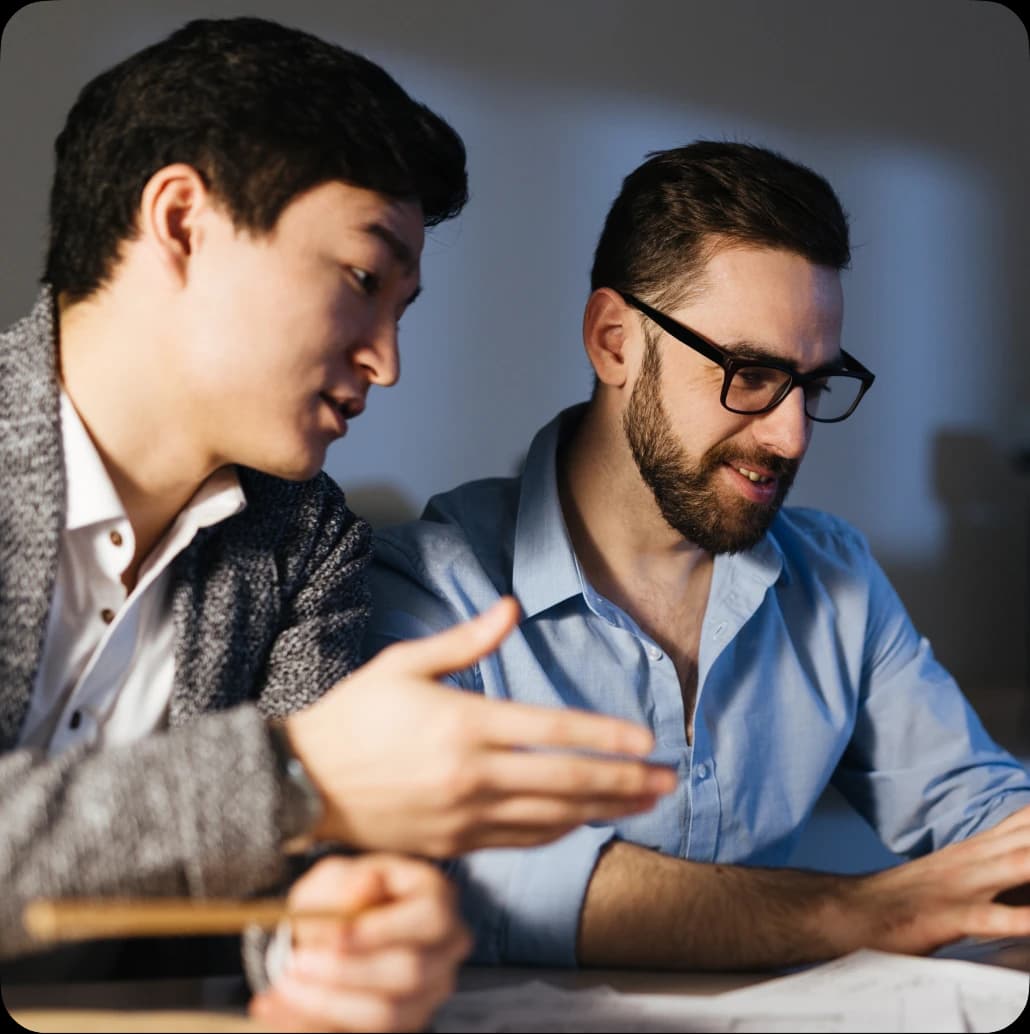 Two men collaborating at a desk during the smart-home design project.