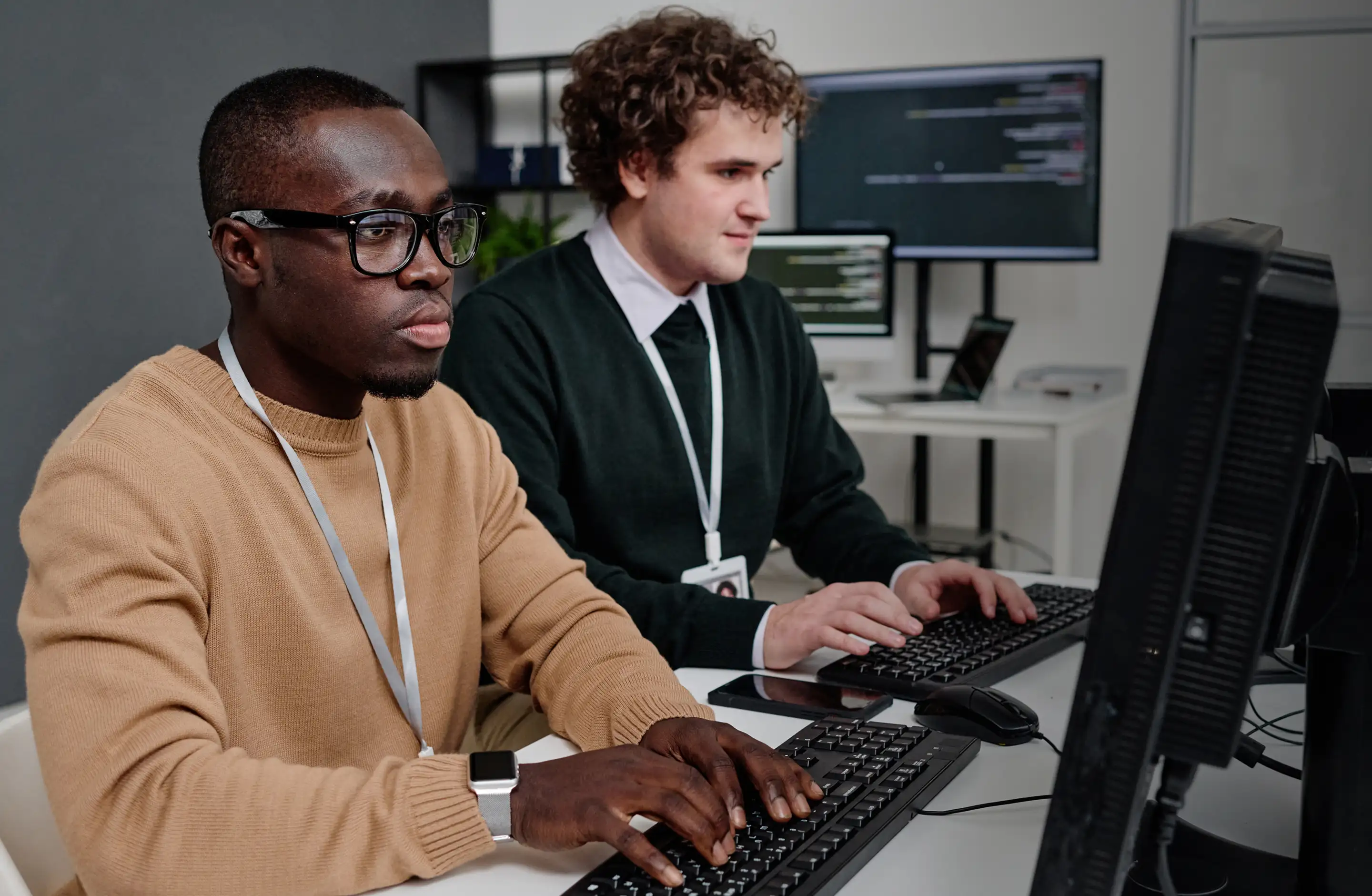 Two developers collaborating at a desk with monitors during platform development.